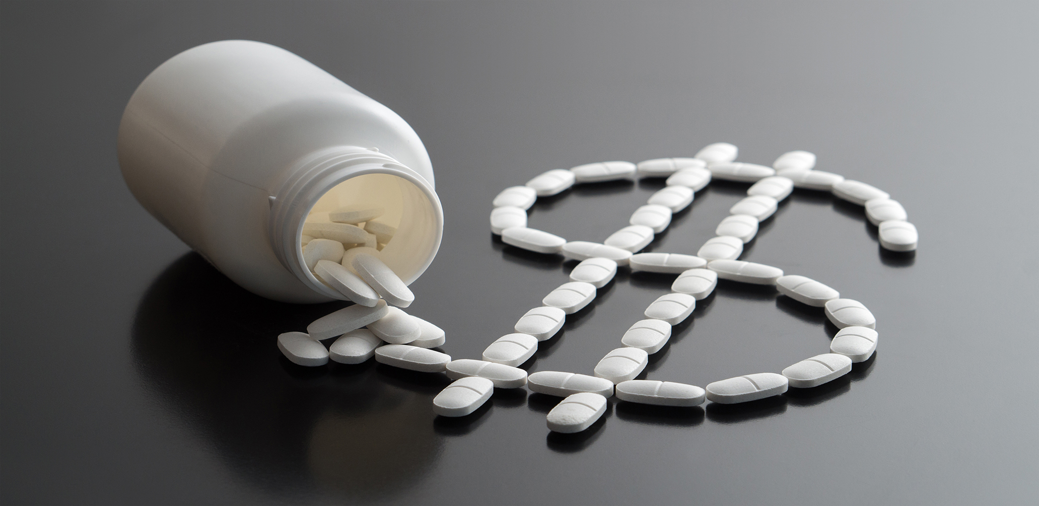Medical business or prices concept. Making money in pharmaceutical industry or high medical expenses. Dollar sign written with pills spilled from a medicine bottle