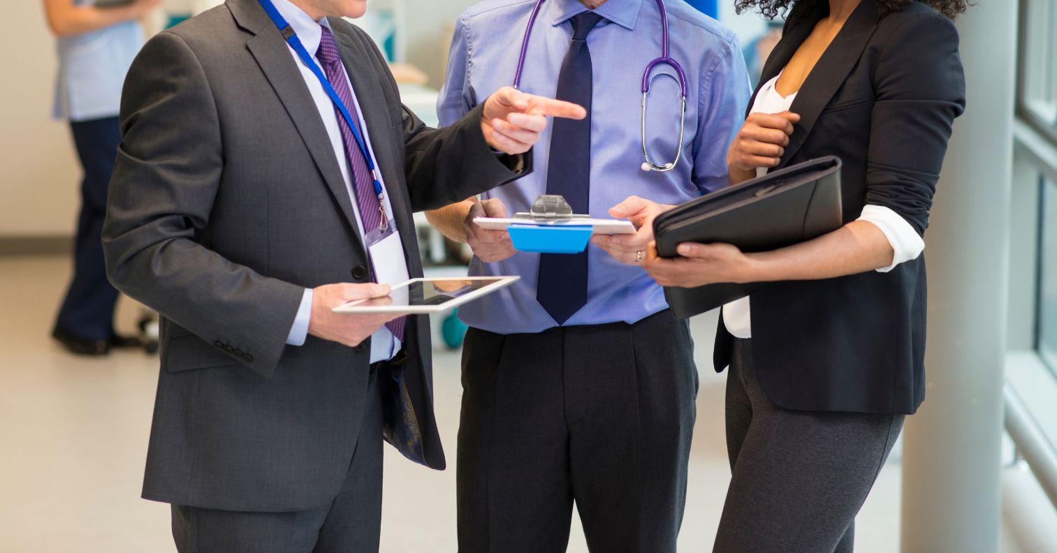 Doctor and colleagues reviewing tablet data in hospital hallway