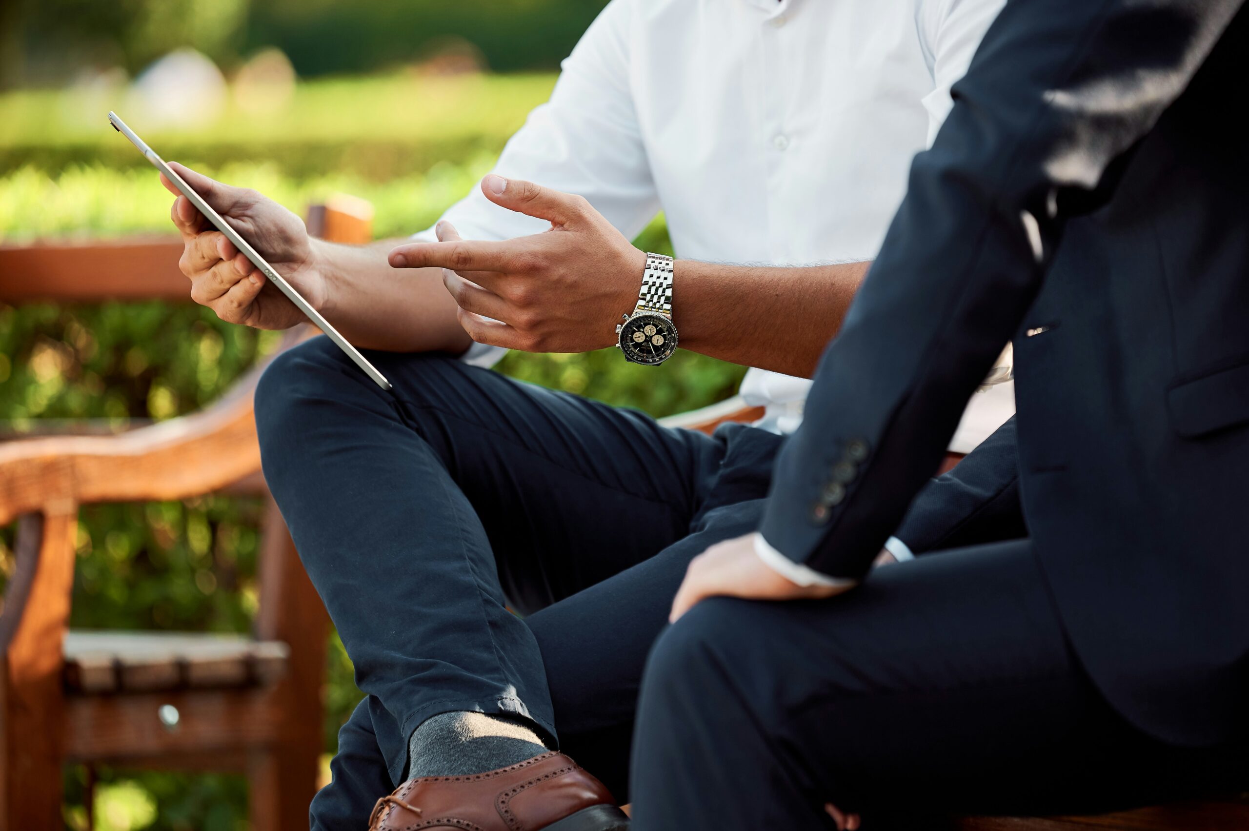 Businessmen discussing tablet while seated outdoors on bench